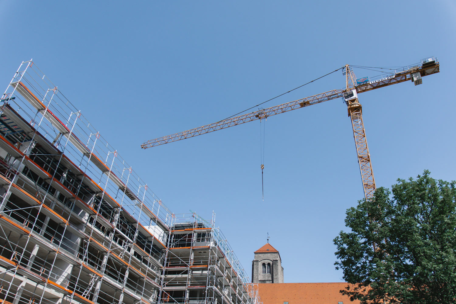 Kran vor neugebautem Haus mit Gerüst